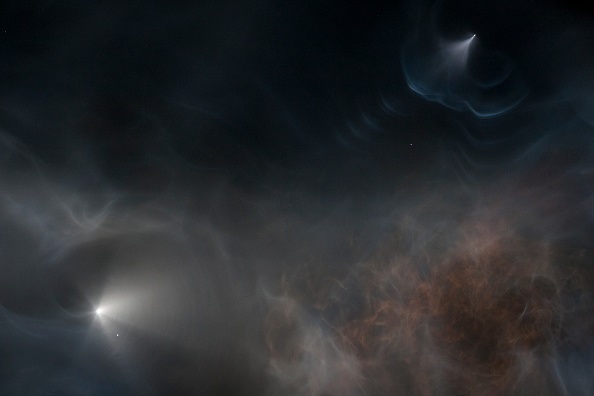 The SpaceX Falcon 9 rocket (upper R) separates from the spacecraft (L) behind the rocket trail