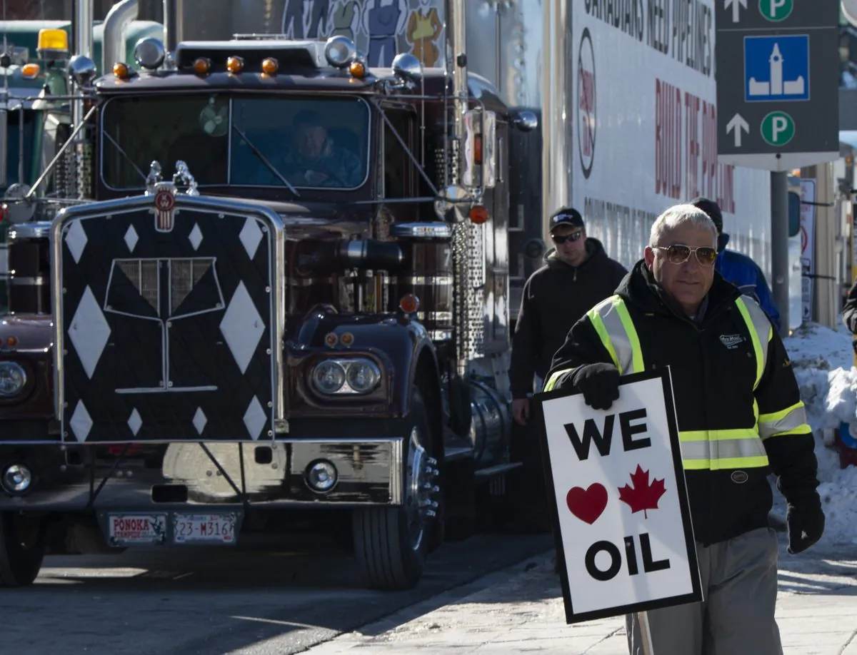 A pro-oil protester stands near convoy vehicles in front of Parliament Hill in Ottawa, Feb. 19, 2019. (The Canadian Press/Adrian Wyld)