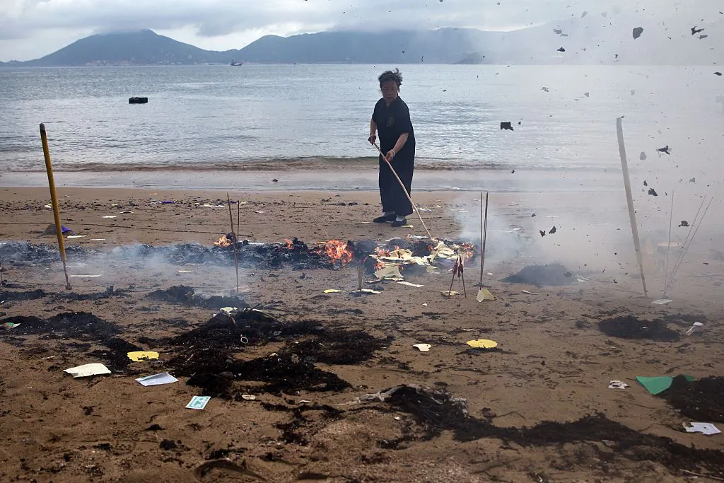 A worker burns offerings on a beach at Joss House temple to celebrate the Tin Hau festival in Hong Kong on May 10, 2015. (Dale de la Rey/AFP/Getty Images)