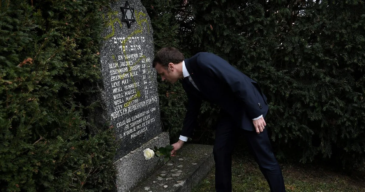 French President Emmanuel Macron lays a white rose on a grave vandalised with swastikas during a visit at the Jewish cemetery in Quatzenheim, France on Feb. 19, 2019. (Frederick Florin/Pool via Reuters)