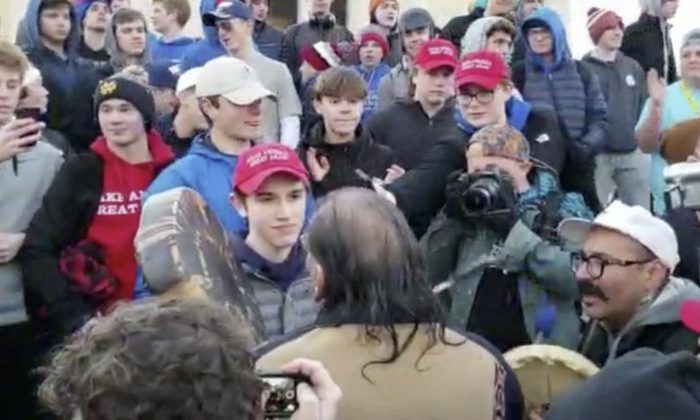 Covington Catholic High School student Nick Sandmann (center L), wearing a Make America Great Again hat, looks at Native American anti-Trump activist Nathan Phillips (center bottom) after being approached by the man in Washington, on Jan. 18, 2019. (Survival Media Agency via AP)