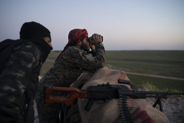 U.S.-backed Syrian Democratic Forces (SDF) fighters watch as an airstrike hits territory still held by Islamic State militants