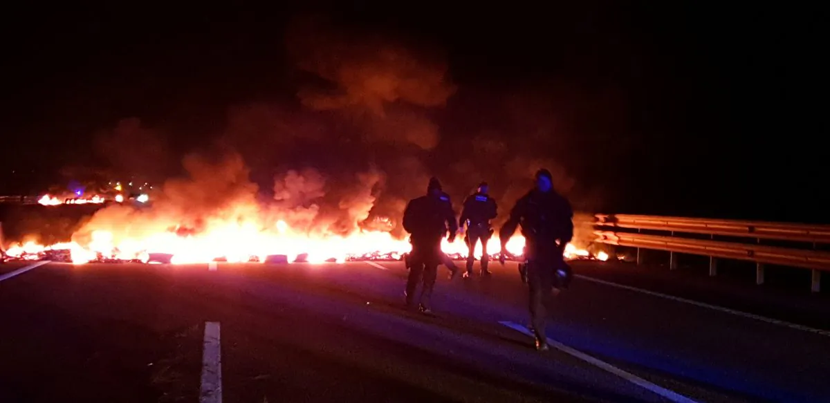 Police officers stand next to burning barricades during a protest near Girona, Spain, on Feb. 21, 2019. (Pilar Suarez/Reuters)