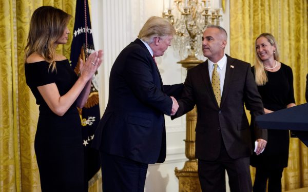Andrew Pollack (C), father of Stoneman Douglas High School mass shooting victim Meadow Pollack, shakes hands with President Donald Trump (2nd L) as first lady Melania Trump (L), Julie Phillips Pollack (2nd R), and Hunter Pollack (R) watch during a Hanukkah reception at the White House