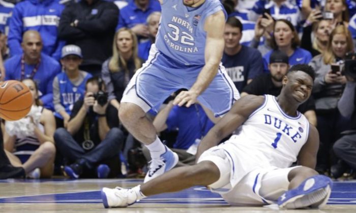 Duke's Zion Williamson (1) falls to the floor with an injury while chasing the ball with North Carolina's Luke Maye (32) during the first half of an NCAA college basketball game in Durham, N.C., Wednesday, Feb. 20, 2019. (AP Photo/Gerry Broome)