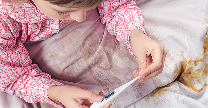 The little girl in a pajamas looks at a thermometer