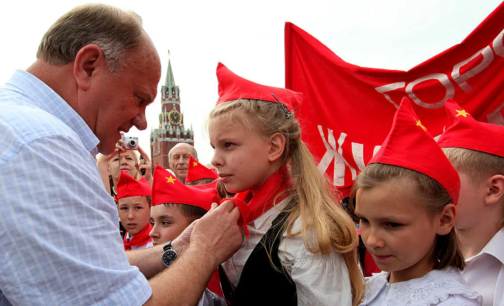 Gennady Zyuganov, leader of the Russian Communist Party ties red scarves around childrens’ necks, symbolizing their initiation into the Young Pioneer Youth communist group created in the Soviet Union for children 10–14 years old, in Moscow’s Red Qquare in this file photo. (Alexey SAZONOV/AFP/Getty Images)