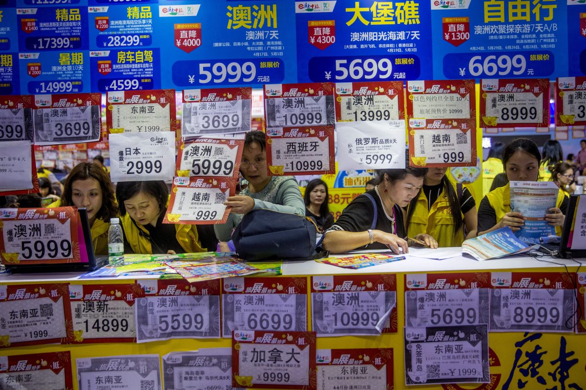 People check on travel packages offered by travel agencies during the Guangzhou International Travel Fair in Guangzhou in south China's Guangdong Province on March 3, 2018. Travelers in China were blocked from buying plane tickets 17.5 million times in 2018 as a penalty for failing to pay fines or other offenses, the Chinese regime reported this week on penalties imposed under a controversial "social credit" system. (Chinatopix via AP)