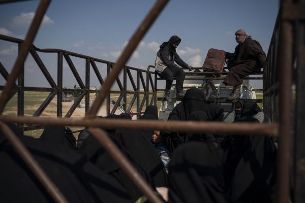 Men, women, and children ride in the back of a truck