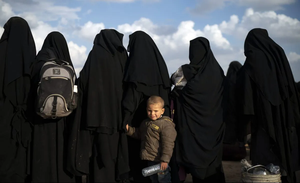 A boy holds her mother's hand as they wait to be screened after being evacuated out of the last territory held by ISIS terrorists, near Baghouz, eastern Syria, on Feb. 22, 2019. (Felipe Dana/AP Photo)