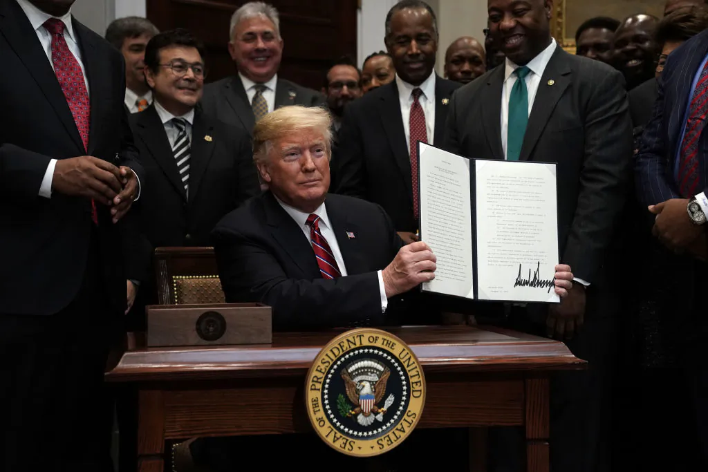 President Donald Trump signs an executive order to establish the White House Opportunity and Revitalization Council as Secretary of Housing and Urban Development Secretary Ben Carson and Sen. Tim Scott (R-SC) look on at the Roosevelt Room of the White House in Washington on Dec. 12, 2018. (Alex Wong/Getty Images)