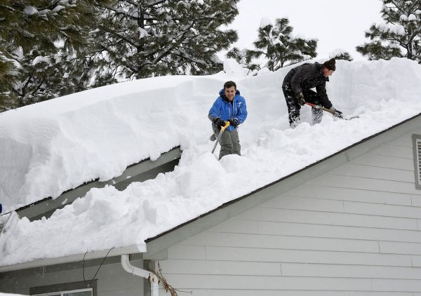 Homeowner Kevin Ireland, right, and Tommy Tokarczyk clear several feet of snow off