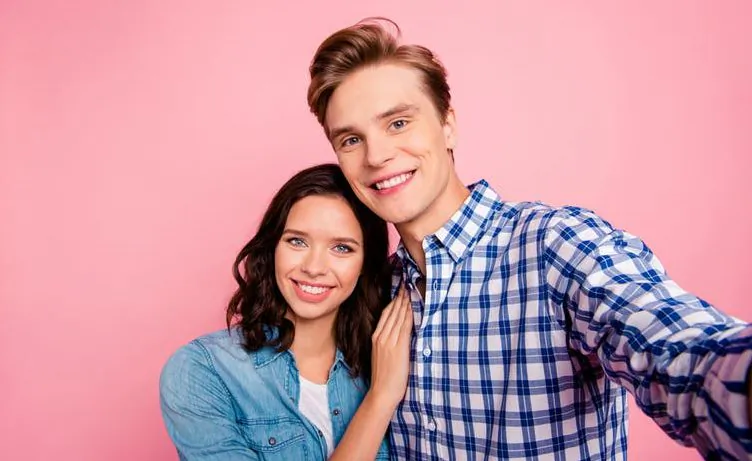 A young couple posing for a selfie could accidentally complicate their relationship by adding in new layers of approval seeking.
(RomanSamborskyi/Shutterstock)