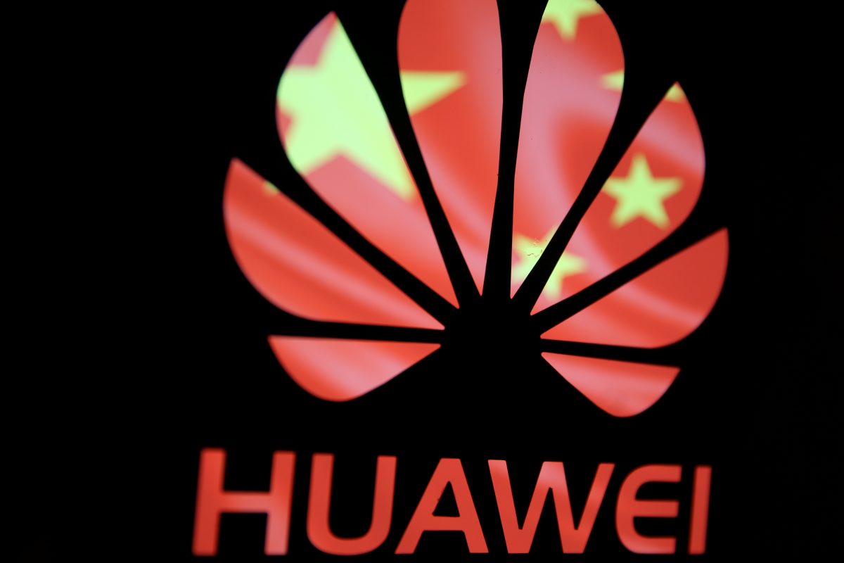 A Huawei logo is seen in front of the Chinese Communist Party flag
