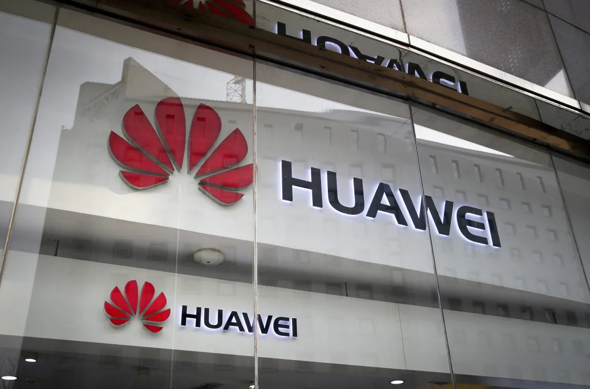 The logos of Huawei are displayed at it retail shop window reflecting the Ministry of Foreign Affairs office in Beijing on Jan. 29, 2019. (Andy Wong/AP)