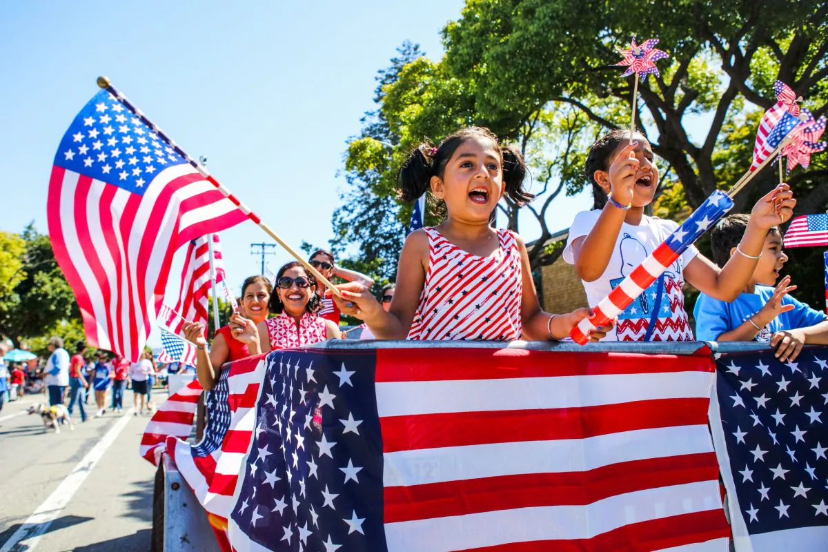 People wave American flags as they ride through the Fourth of July Parade in Alameda, Calif., on Jul. 4, 2016. (Gabrielle Lurie/AFP/Getty Images)