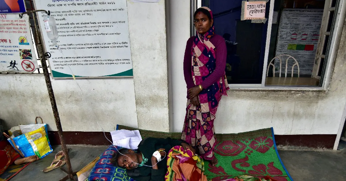 The wife of a tea plantation worker, who consumed bootleg liquor, looks on as she stands next to her husband being treated, in a corridor of a government-run hospital in Golaghat in the northeastern state of Assam, India, Feb. 23, 2019. (Anuwar Hazarika/Reuters)