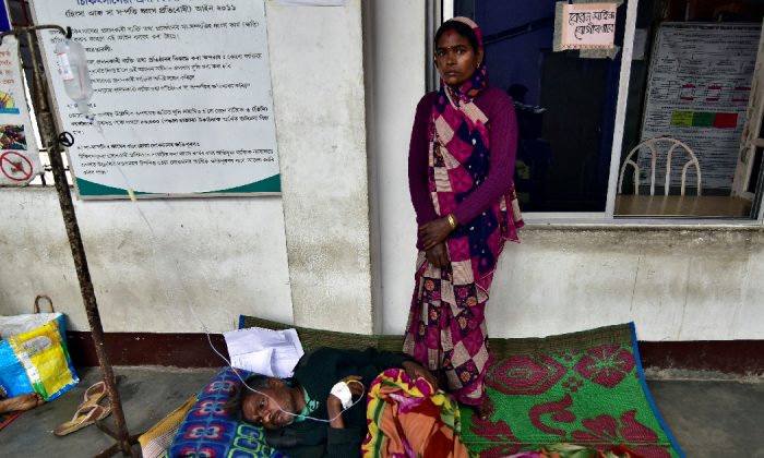 The wife of a tea plantation worker, who consumed bootleg liquor, looks on as she stands next to her husband being treated, in a corridor of a government-run hospital in Golaghat in the northeastern state of Assam, India, Feb. 23, 2019. (Anuwar Hazarika/Reuters)
