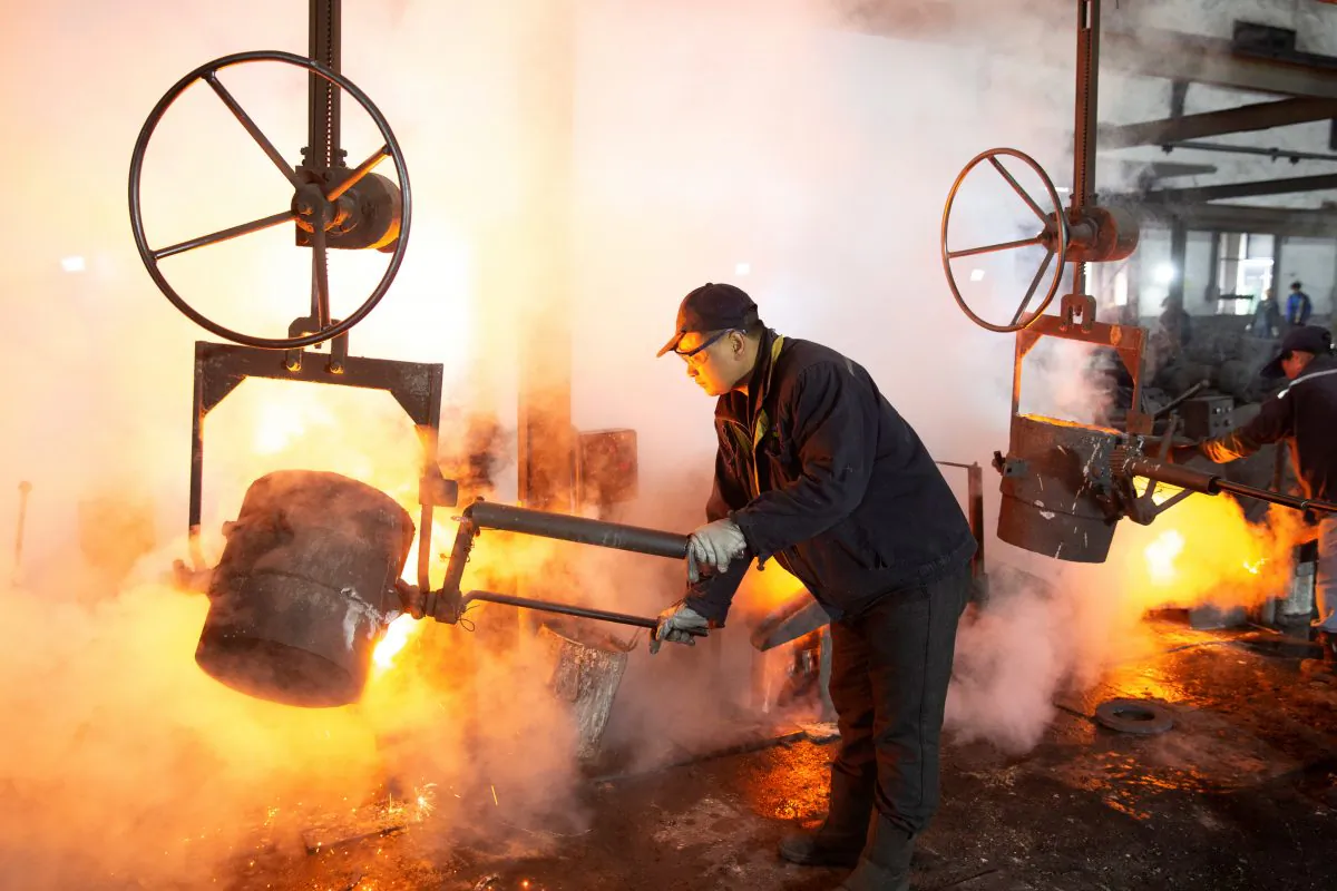 A worker pours molten iron into a mould at a mill manufacturing marine engine components in Huaian, Jiangsu Province, China on Feb. 11, 2019. (Reuters)