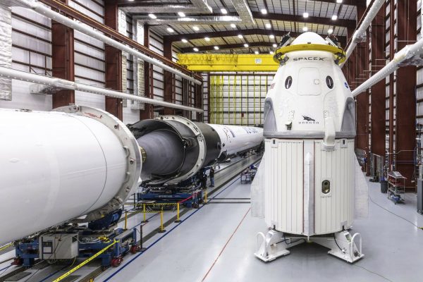 SpaceX's Crew Dragon spacecraft and Falcon 9 rocket are positioned inside the company's hangar