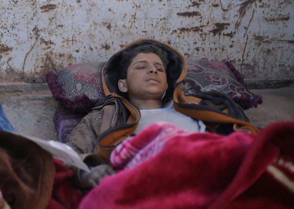 Hareth Najem, an Iraqi orphan lies under a blanket in a truck,