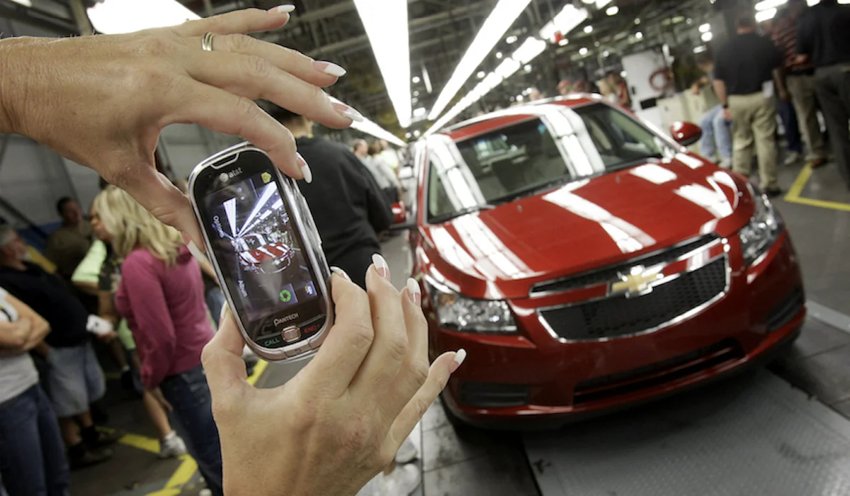 An auto worker takes a picture of the first Chevrolet Cruze compact sedan to come off the assembly line at a ceremony inside the GM factory in Lordstown, Ohio. On Sept. 8, 2010. (AP Photo/Amy Sancetta)