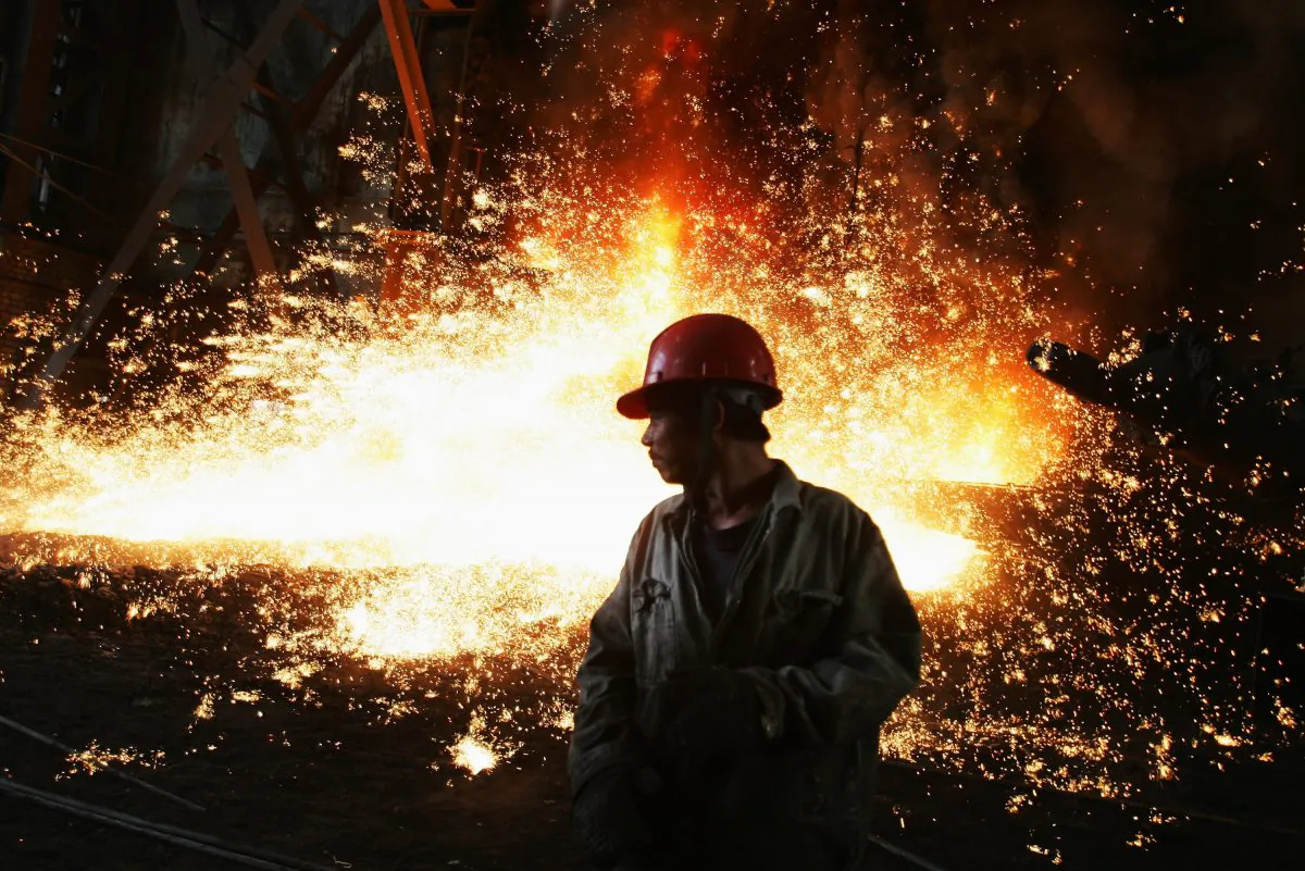 A worker with molten iron flowing up in the iron-smelting workshop at the Chengde Steel Plant in Chengde City, Hebei Province, China on Oct. 11, 2007. (Feng Li/Getty Images)