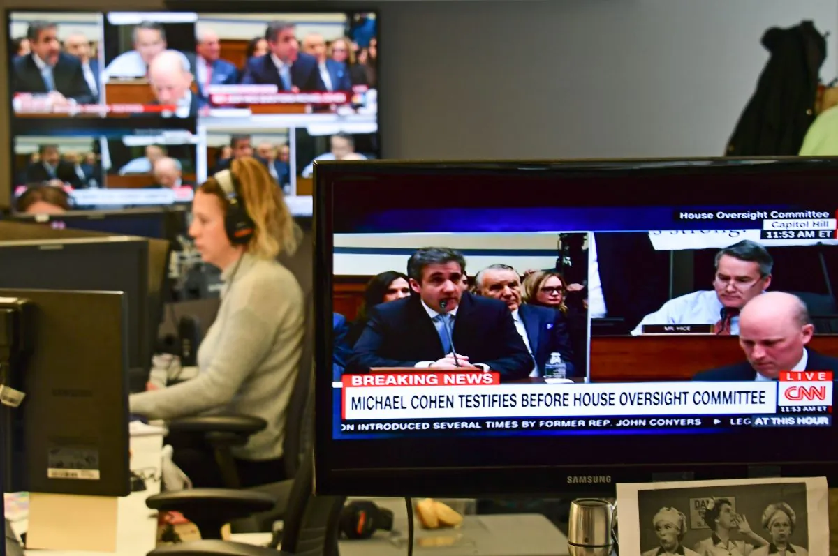 View of television screens inside a newsroom as they air live Michael Cohen's testimony before the House Oversight and Reform Committee on Feb. 27, 2019. (EVA HAMBACH/AFP/Getty Images)
