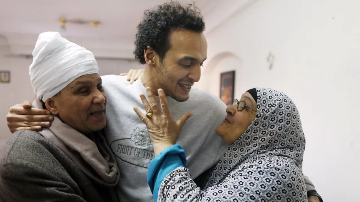 Mahmoud Abu Zaid, center, a photojournalist known as Shawkan, is hugged by his parents at his home in Cairo, Egypt, on March 4, 2019. (Amor Nabil/AP Photo)