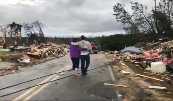 People walk amid debris in Lee County, Ala.