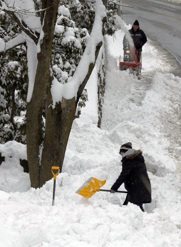 Residents clear snow after an overnight snowstorm dropped nearly a foot of snow