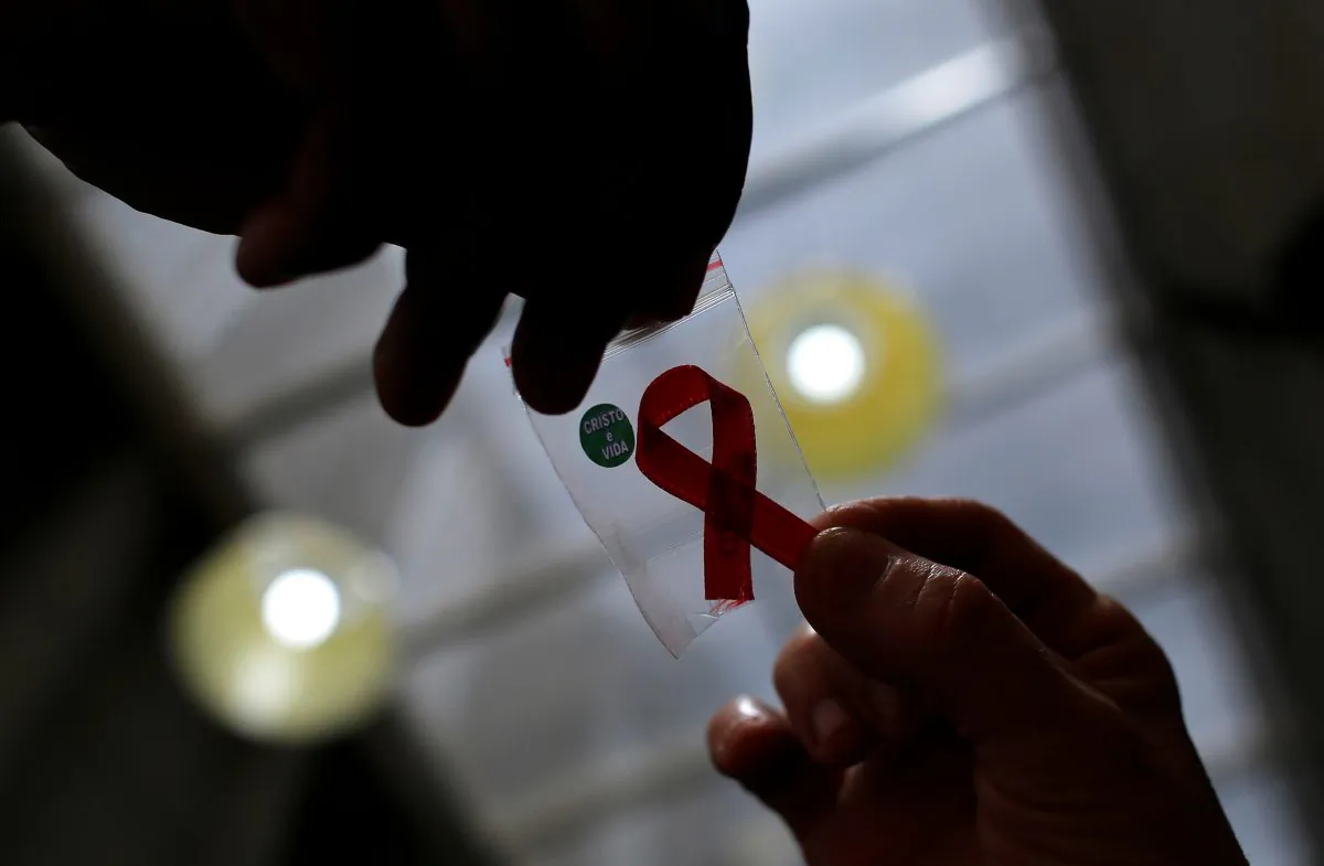 A nurse (L) hands out a red ribbon to a woman, to mark World Aids Day, at the entrance of Emilio Ribas Hospital, in Sao Paulo, on Dec. 1, 2014. (Nacho Doce/Reuters File Photo)