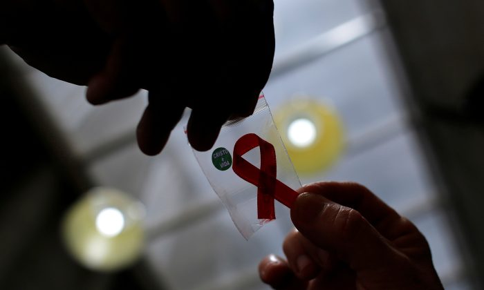 A nurse (L) hands out a red ribbon to a woman, to mark World Aids Day, at the entrance of Emilio Ribas Hospital, in Sao Paulo, on Dec. 1, 2014. (Nacho Doce/Reuters File Photo)