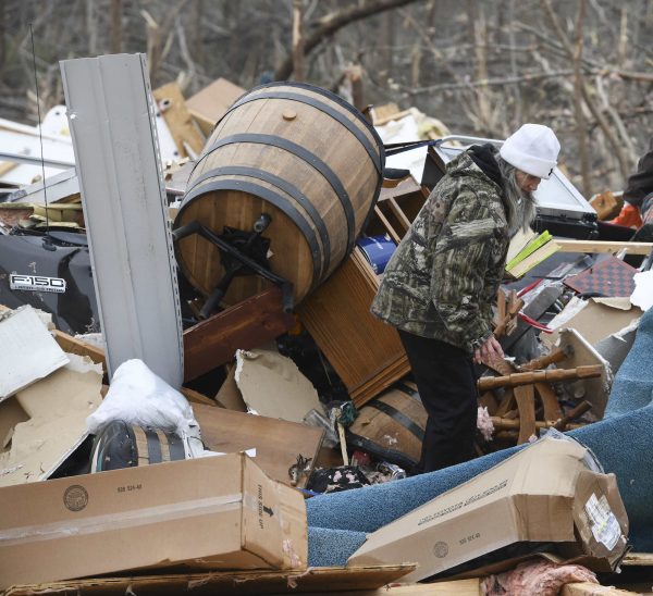 a woman looks through the debris of her home