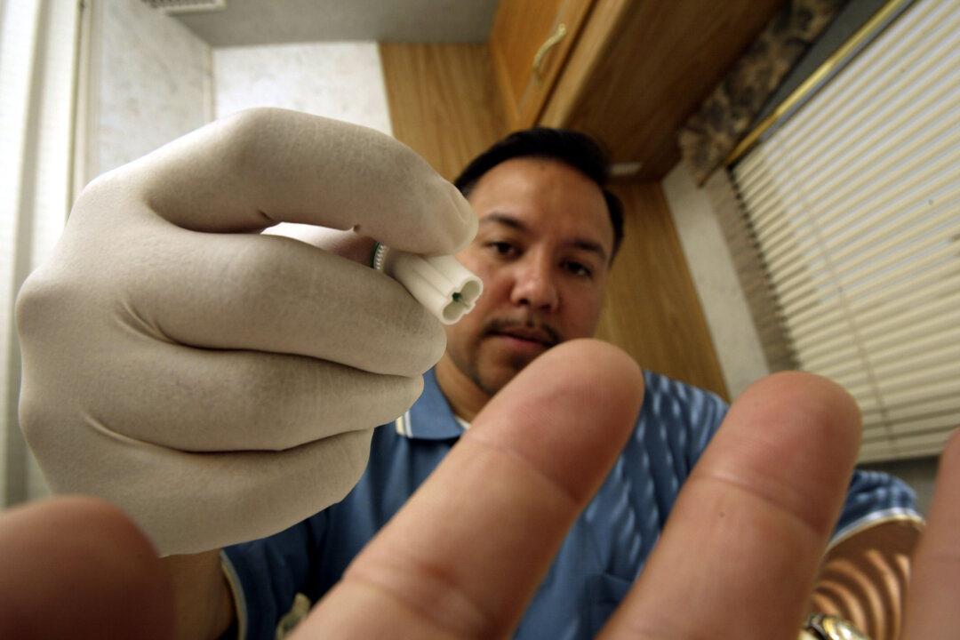 Joe Mendoza, AIDS Healthcare Foundation (AHF) mobile testing program manager, uses the photographer's finger to demonstrate how a lancet from the OraQuick Rapid HIV-1 Antibody Test kit would be used to obtain a blood sample inside the AHF mobile HIV screening lab on its first day of operations in Los Angeles, Calif. on Apr. 28, 2004. (David McNew/Getty Images)
