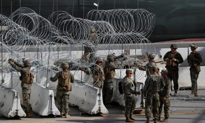 U.S. Marines help to build a concertina wire barricade at the U.S. Mexico border in preparation for the arrival of a caravan of migrants at the San Ysidro border crossing in San Diego, Calif., on Nov. 13, 2018. (Reuters/Mike Blake)


