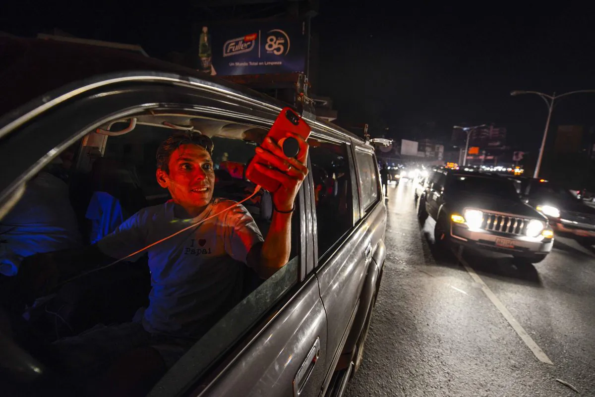 People use their mobile phones at the Francisco Fajardo highway—where they can get telephone service—during a partial power outage in Caracas, Venezuela, on March 9, 2019. (Matias Delacroix/AFP/Getty Images)