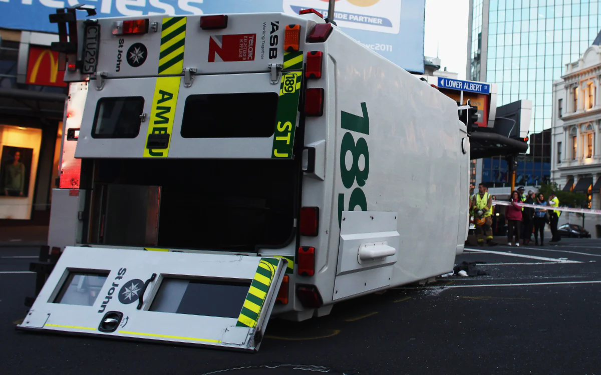 An ambulance lies on its side after colliding with a black Audi at the corner Custom St West and Lower Albert St in Auckland, New Zealand on Nov. 2, 2010. (Hannah Peters/Getty Images)