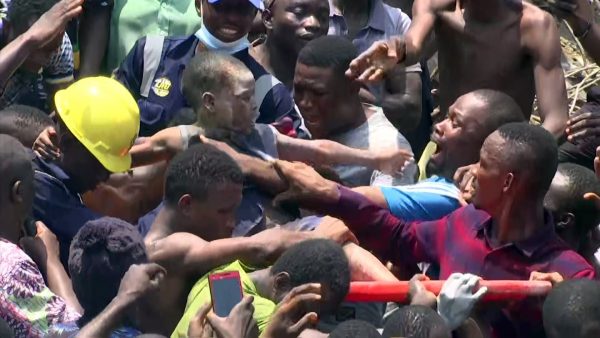 In this image taken from video, people help a child after he was rescued from the scene of a building collapse