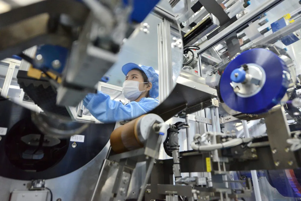 The reflection of a worker is seen at the production line of lithium-ion batteries for electric vehicles at a factory in Huzhou, Zhejiang Province, China, on Aug. 28, 2018. (Stringer/Reuters)