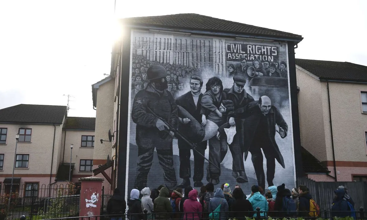 Tourists stand in front of a mural depicting Bloody Sunday, in Londonderry, Northern Ireland, on March 14, 2019. (Clodagh Kilcoyne/Reuters)