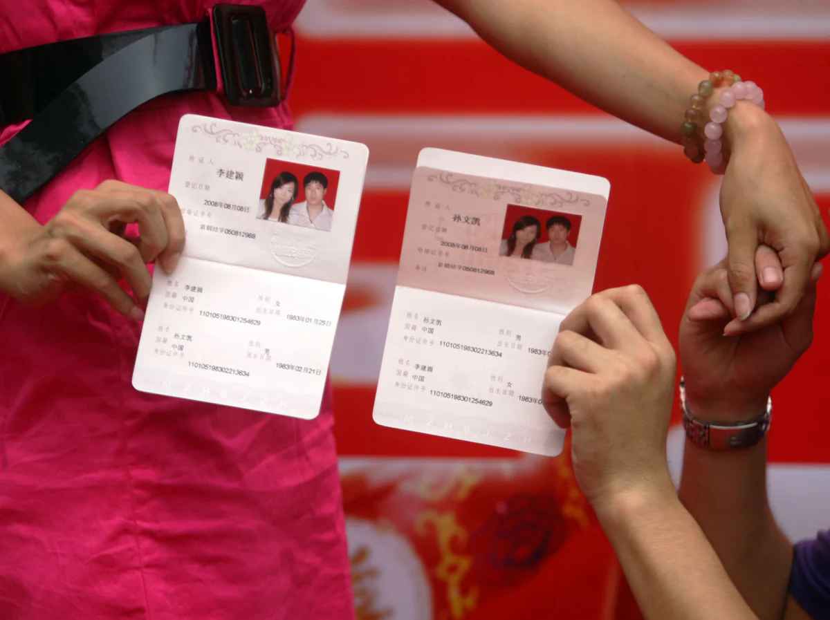 Two newly-weds holding their marriage certificates. (China Photos/Getty Images)