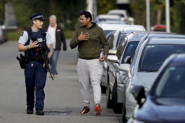 Ash Mohammed, right, talks to a police officer about his father and two brothers who are missing near the Masjid Al Noor mosque