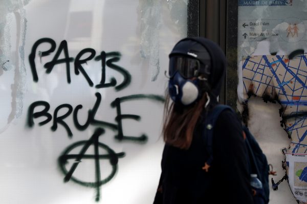 A protester walks past graffiti reading 'Paris burns' 