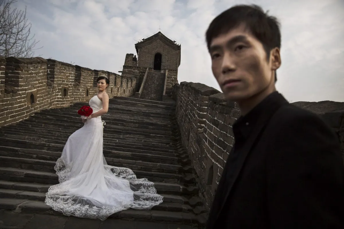 A Chinese bride poses for a wedding photographer as her groom looks on, on a section of the Great Wall of China near Beijing on October 28, 2014. China's marriage rate decreased continually for the past five years and reached the lowest point in 2018. (Kevin Frayer/Getty Images)