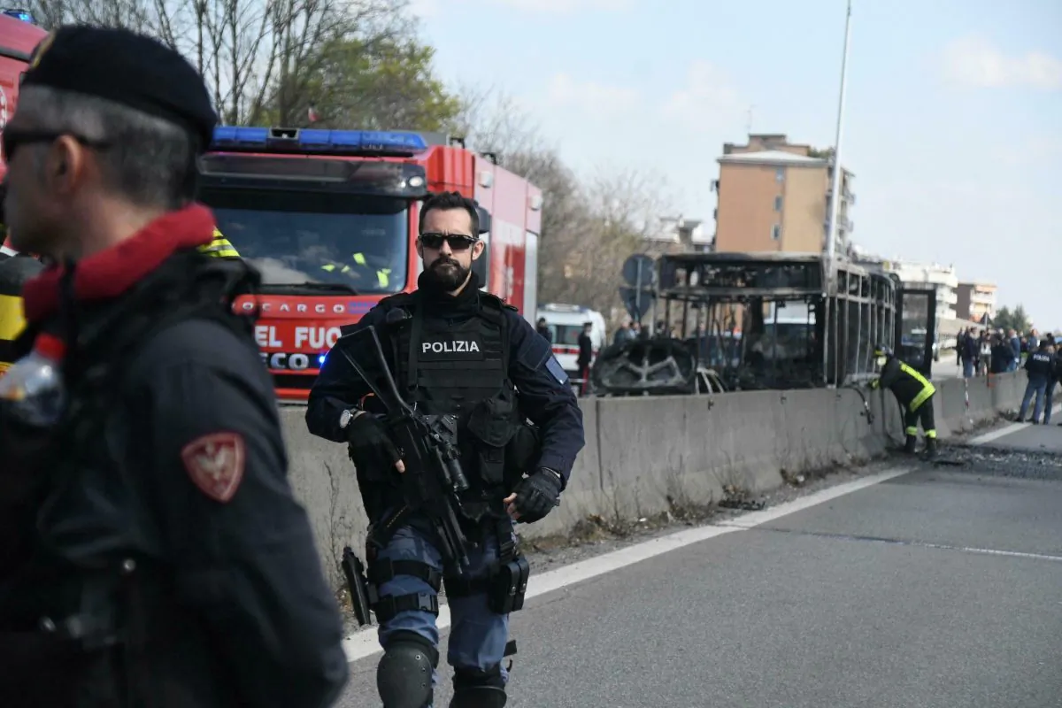 Firefighters and police officers stand by the gutted remains of a bus in San Donato Milanese, near Milan, Italy, on March 21, 2019. (Daniele Bennati/ANSA via AP)