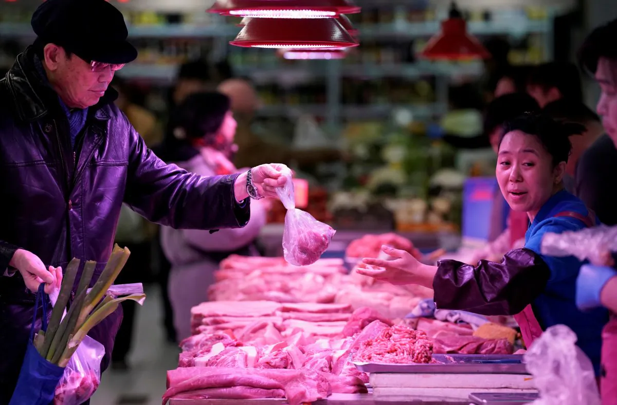 A resident gets pork from a vendor at a market in Beijing on Dec. 26, 2018. (Jason Lee/Reuters)
