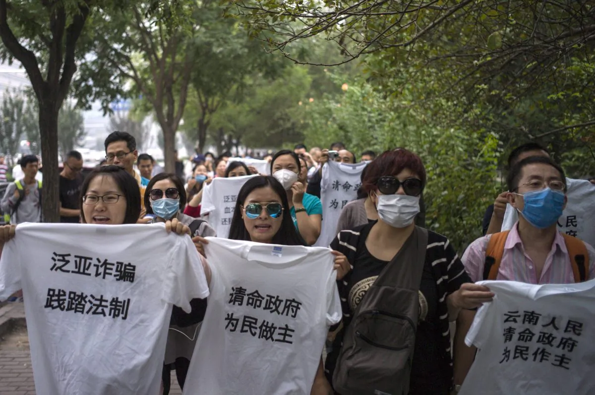 People protest outside the office of China's top anti-graft agency complaining they were tricked by Fanya Metals Exchange. Chinese investors who claim to have lost money on risky investments mounted a rare protest in Beijing on Sept. 22, 2015. (Fred Dufour/AFP/Getty Images)