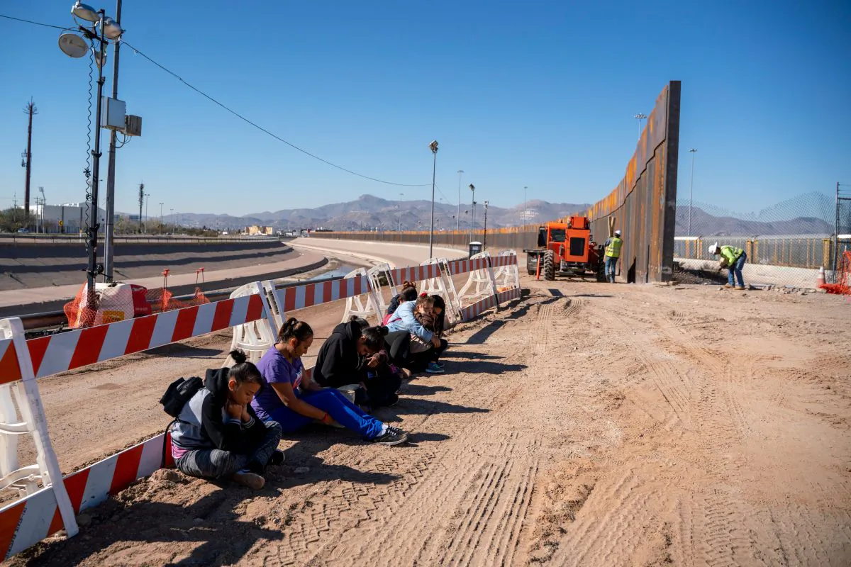 Salvadoran illegal aliens wait for a transport to arrive after turning themselves into U.S. Border Patrol by border fence under construction in El Paso, Texas, on March 19, 2019. (Paul Retje/AFP/Getty Images)