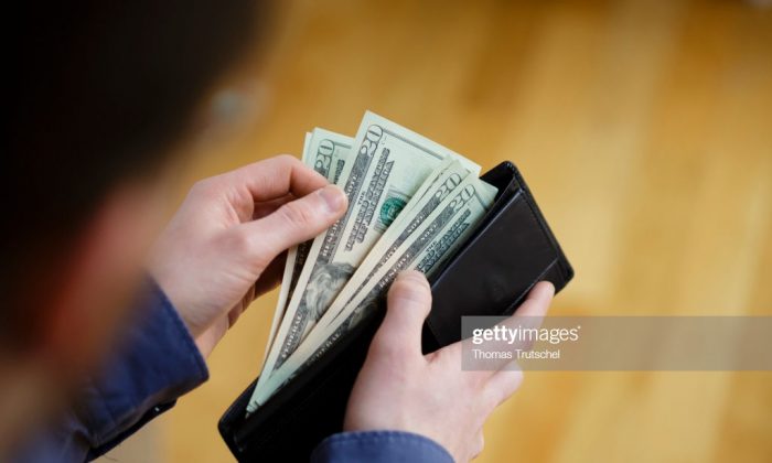 A person holds a wallet filled with U.S. dollar bills in a file photo. (Thomas Trutschel/Photothek via Getty Images)